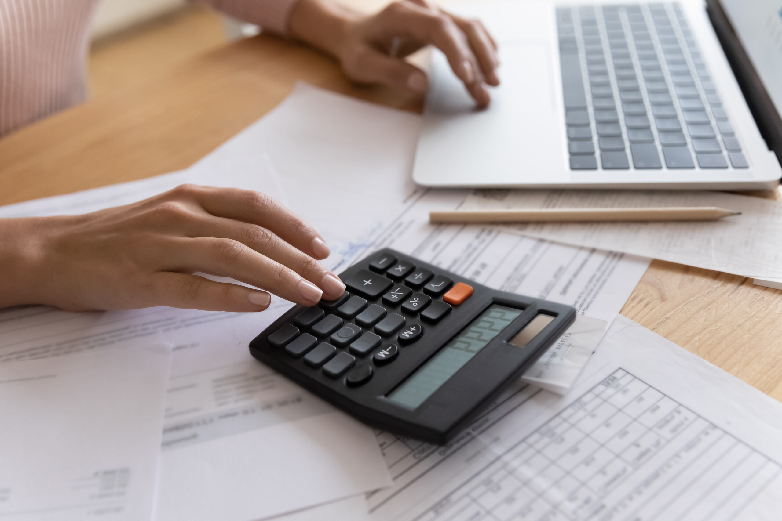 mujer haciendo cuentas con la calculadora y el ordenador sobre como afectan las subidas del precio de la luz