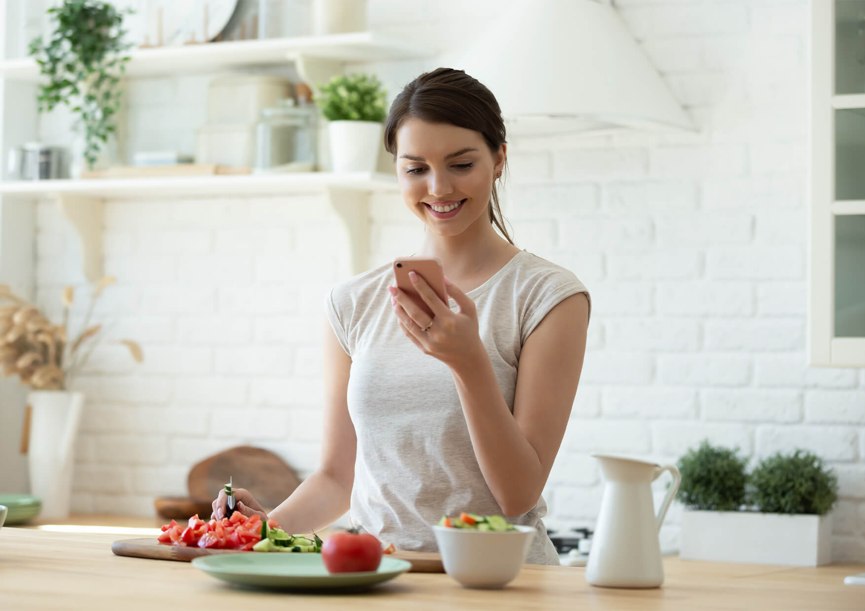 mujer feliz preparando la comida en la cocina mirando trucos y consejos para ahorrar en la cocina