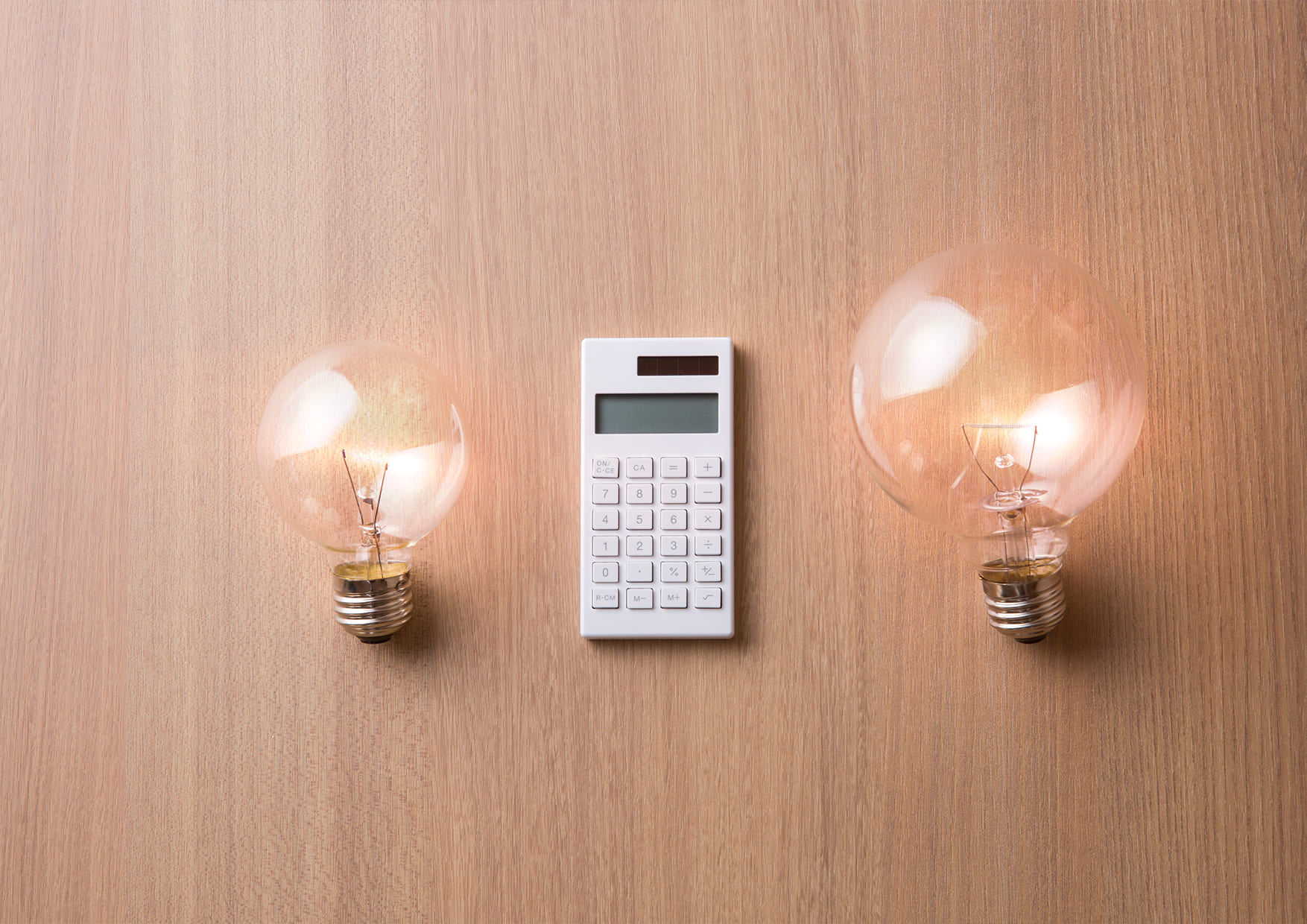 calculadora y bombillas sobre una mesa de madera - que es el coste de la energia