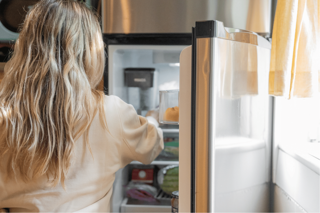 Mujer abriendo la puerta de un frigorifico o electrodomestico eficiente en la cocina