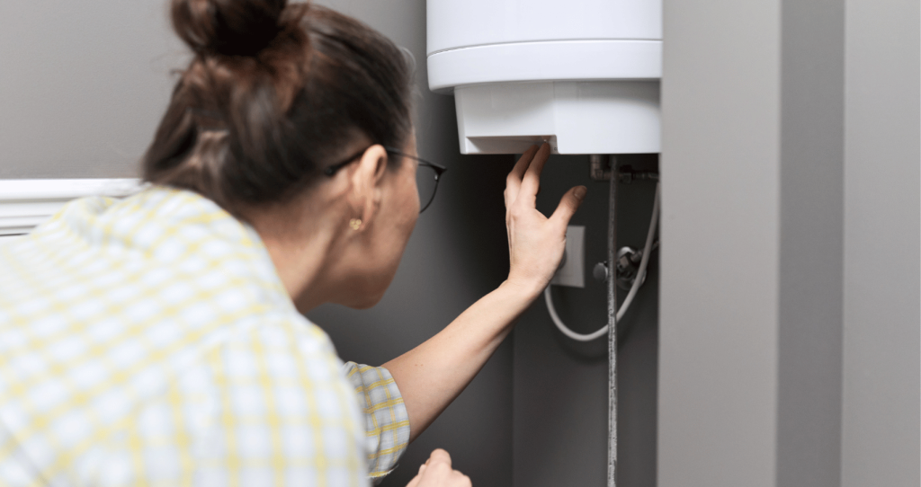 Mujer ajustando la temperatura de un termo electrico o calentador de agua en casa